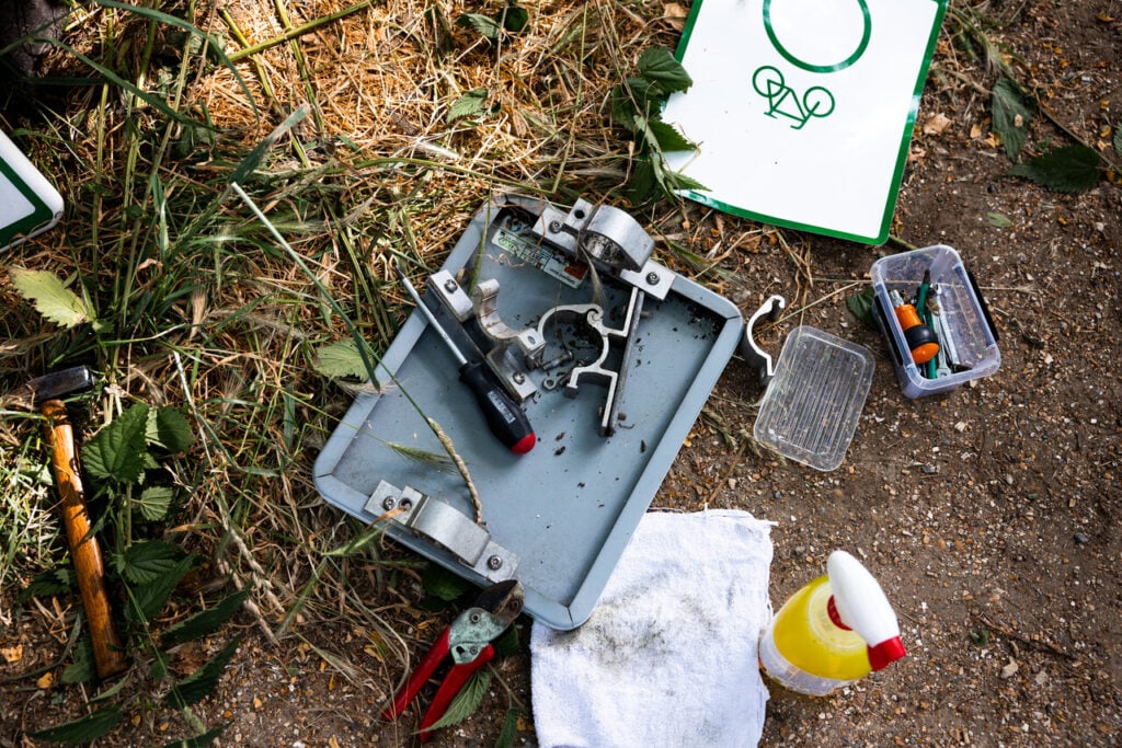 Gereedschap zoals schroevendraaier, hamer, tang en reinigingsspuitmiddel bij een losgemaakt verkeersbord in de natuur van Brabant.