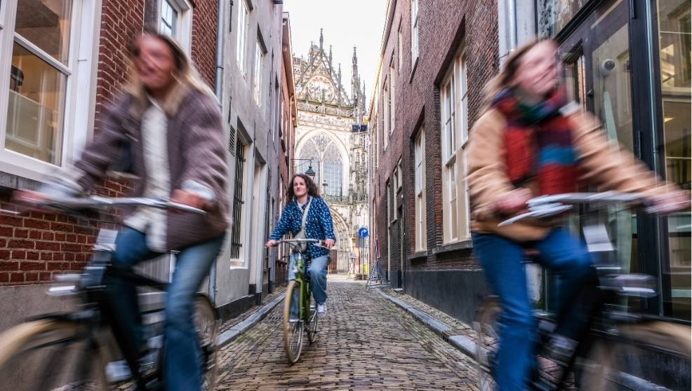 Drie mensen fietsen door een straat in Brabant.