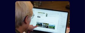 Persoon wijst op een laptop naar een Tripadvisor-pagina met foto's en accommodatietypes in Brabant.