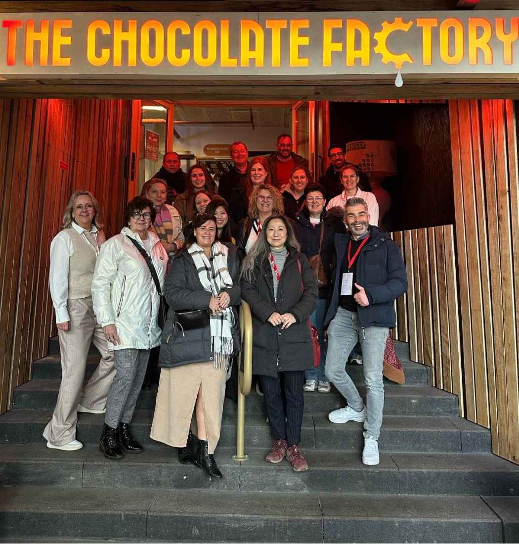 Famtrip in Brabant: groep mensen poseert voor The Chocolate Factory in Veghel, Brabant, onder oranje lichtbord.